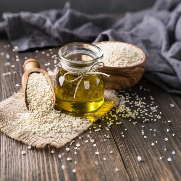 دانههای کنجد تازه و روغن کنجد در ظرف شیشهای