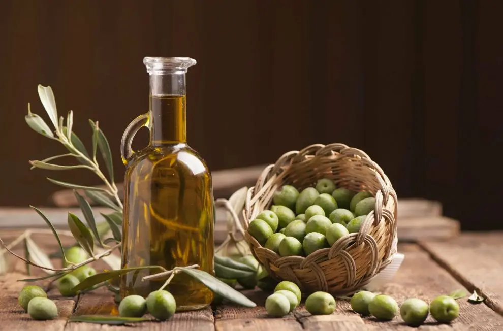 روغن زیتون در داخل یک ظرف شیشه‌ای با قاشق چوبی