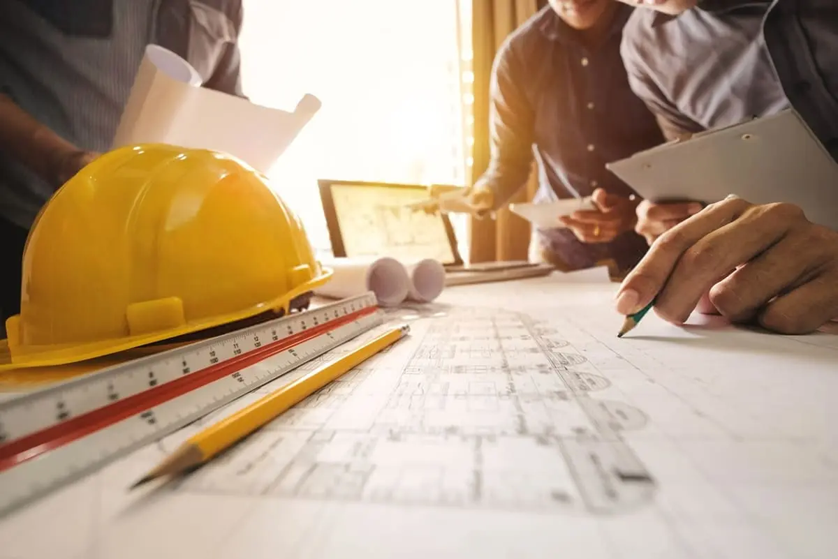 یک مهندس در حال بررسی نقشه و برنامه ساخت با استفاده از نرمافزار مدیریت پروژه