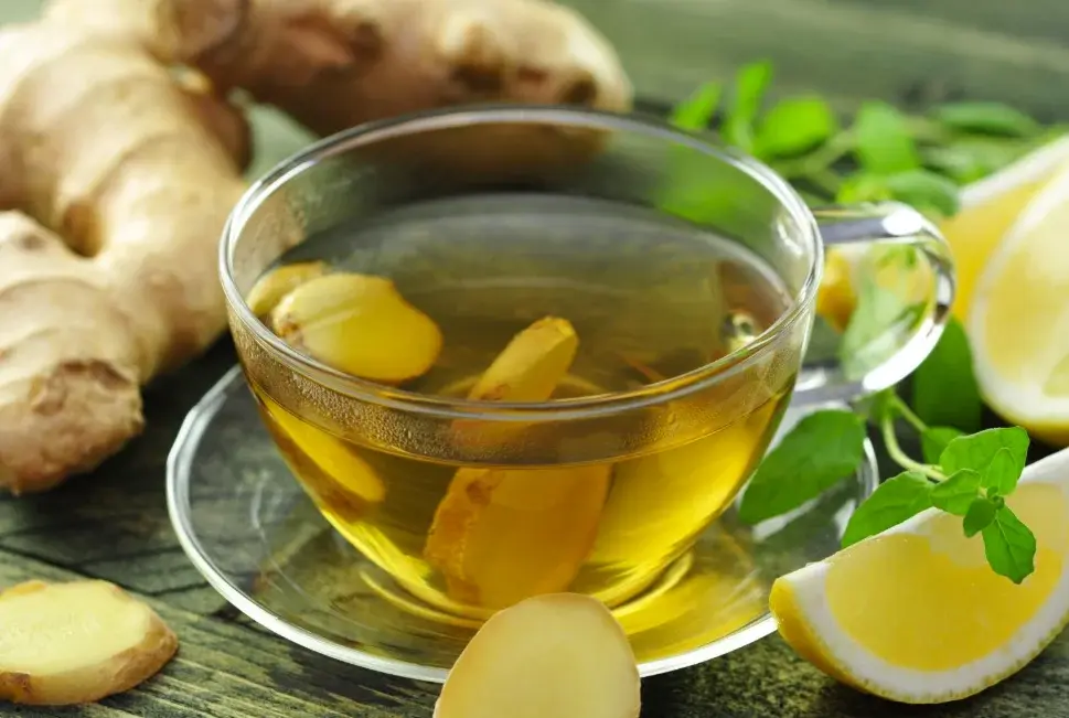 قطعات تازه زنجبیل در کنار فنجان آب جوش