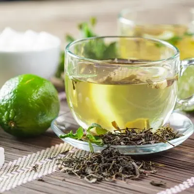 فنجان چای سبز با برگهای نعناع روی میز چوبی