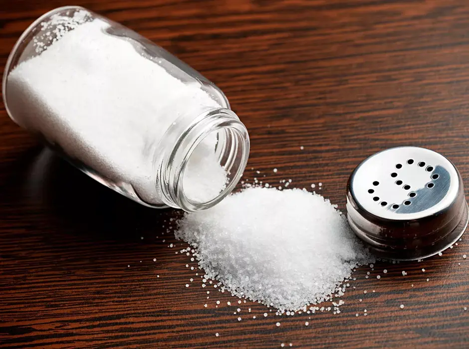 نمک خوراکی در یک ظرف شیشهای با درپوش فلزی و ذرات سفید و ریز
