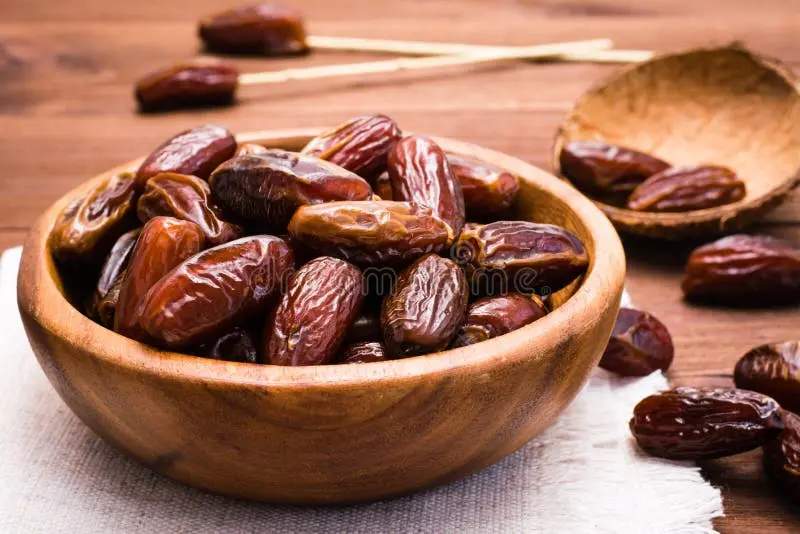 خرماهای شیرین خشک شده داخل کاسه چوبی روی میز