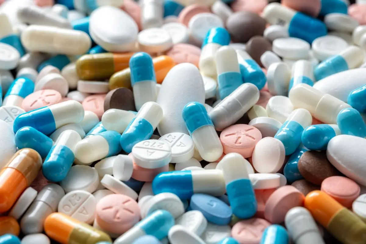 یک پزشک در حال بررسی نسخه دارویی برای یک بیمار، نشاندهنده اهمیت مشورت با متخصص