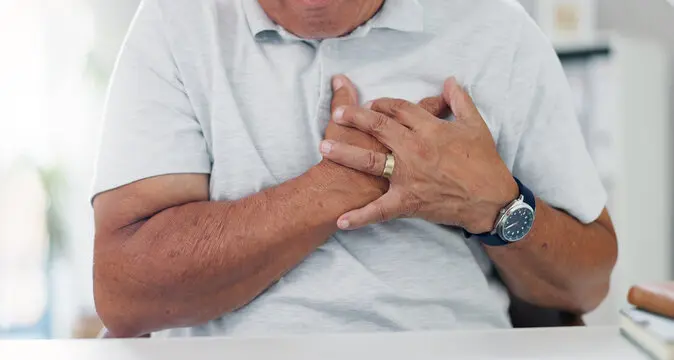 یک فرد در حال بررسی علائم درد قفسه سینه با استفاده از دستگاه اندازهگیری فشار خون