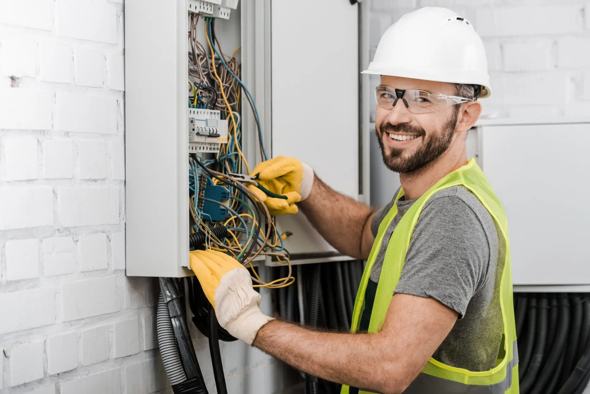 برقکار صنعتی در حال بررسی و تنظیم تجهیزات الکتریکی در یک کارخانه